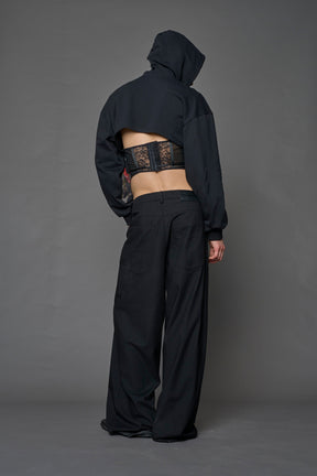 male model wearing a lingerie-inspired black hoodie with a lace corset 