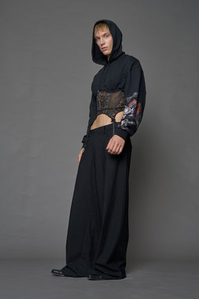 male model wearing a lingerie-inspired black hoodie with a lace corset and a goth-inspired print