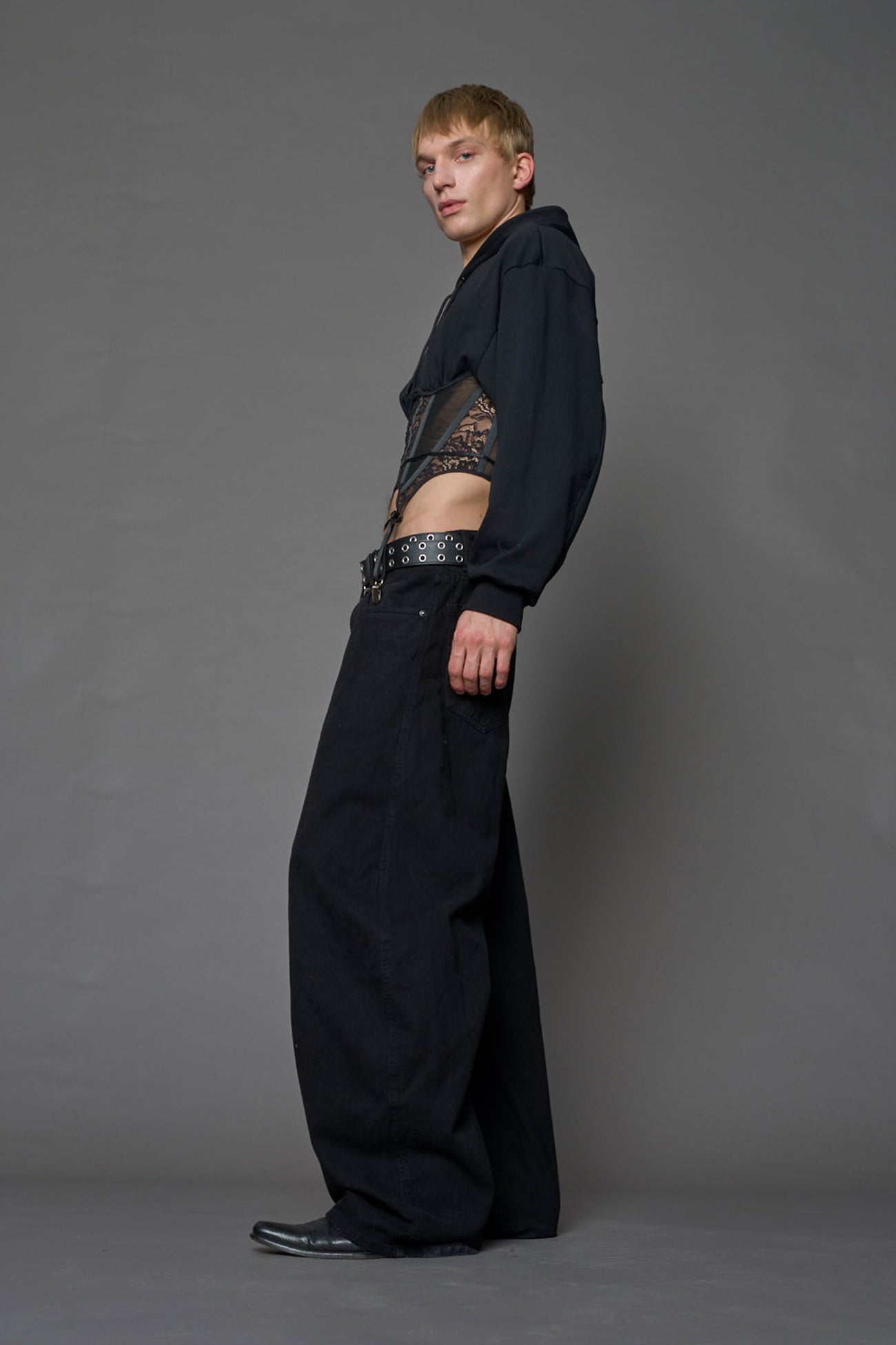 male model wearing a lingerie-inspired black hoodie with a lace corset