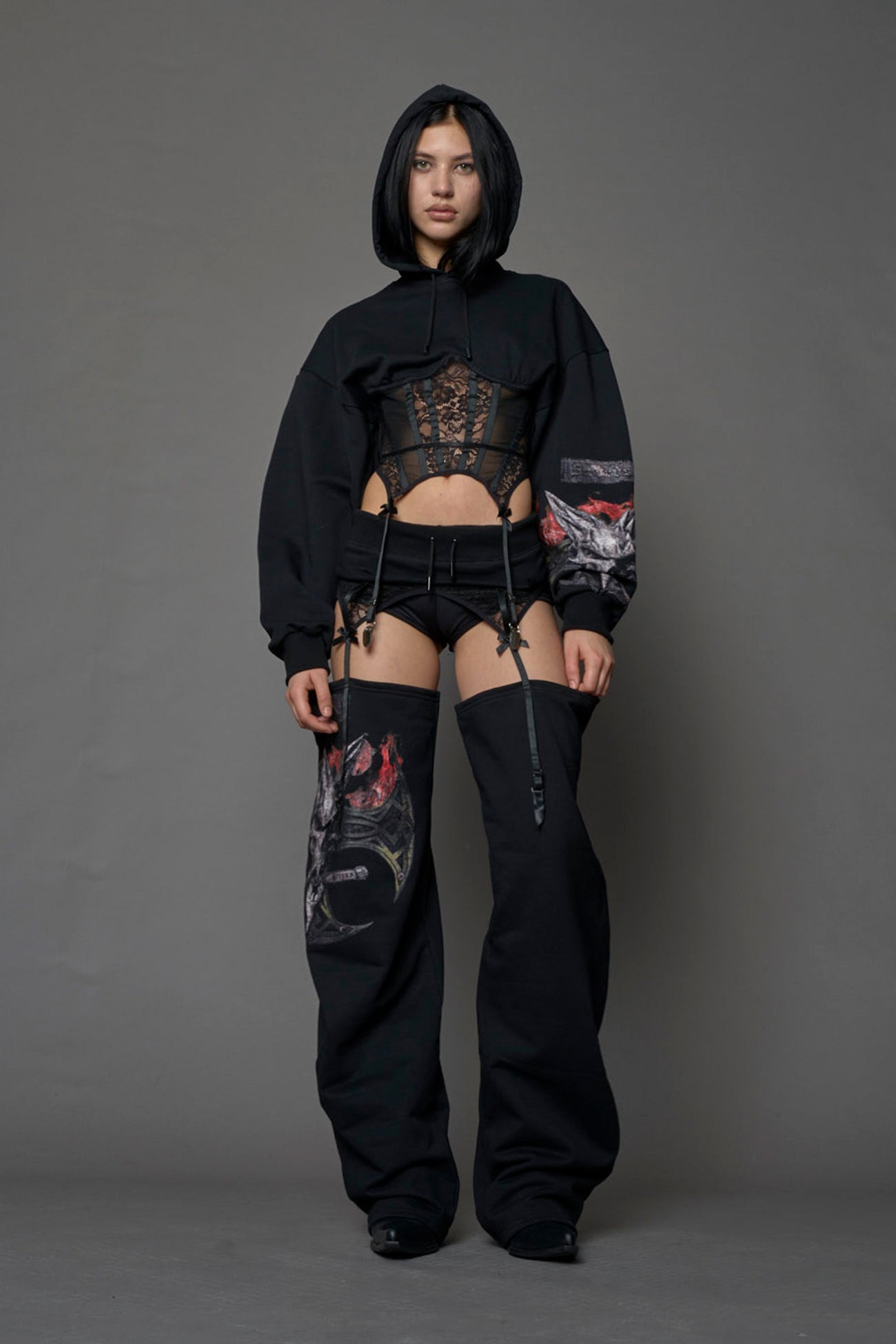female model wearing a lingerie-inspired black hoodie with a lace corset and a goth-inspired print