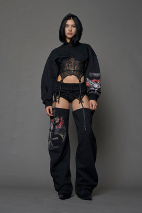 female model wearing a lingerie-inspired black hoodie with a lace corset and a goth-inspired print