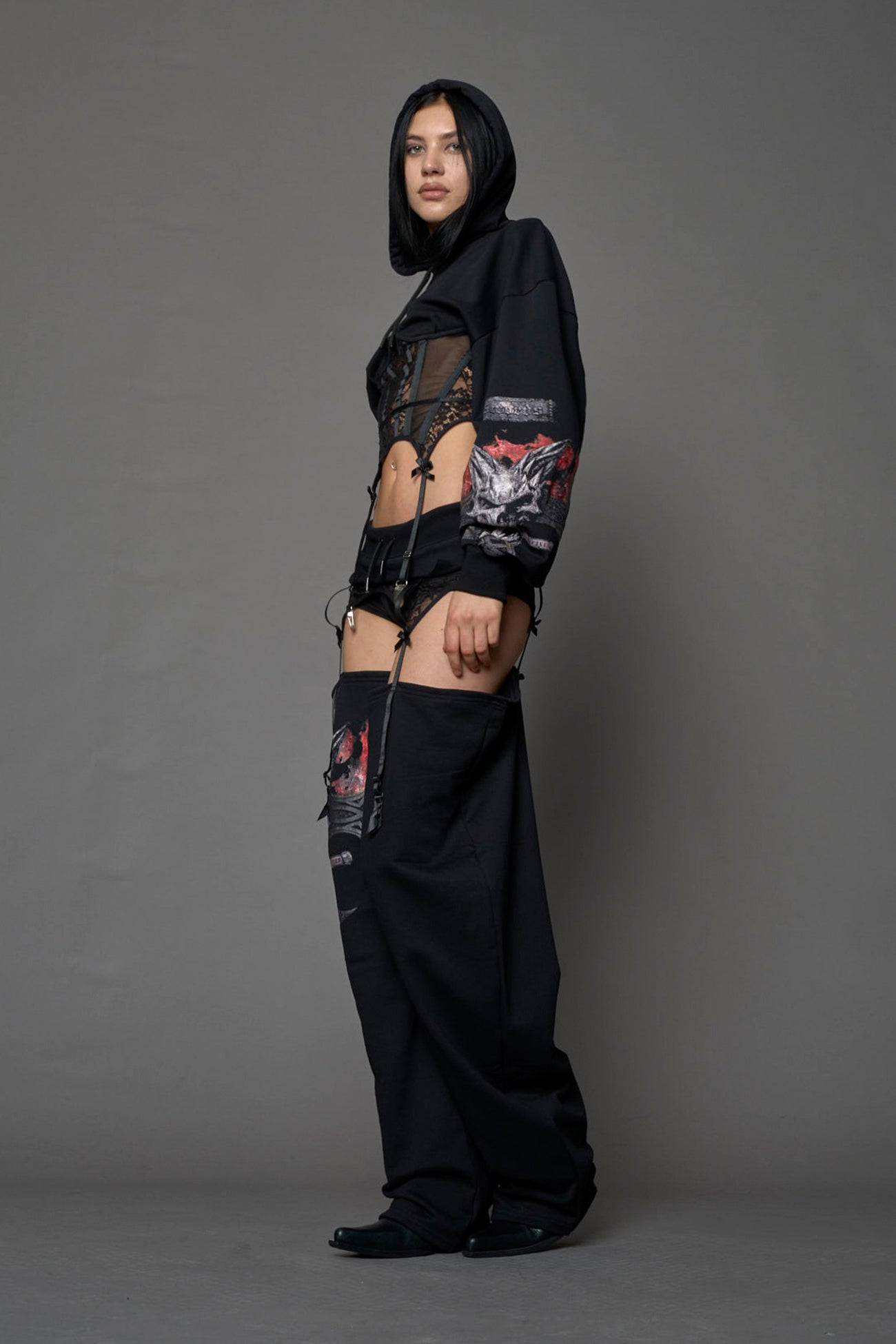 female model wearing a lingerie-inspired black hoodie with a lace corset and a goth-inspired print