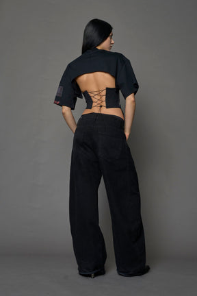 female model wearing a black oversized T-Shirt with a goth-inspired print and a back corset detail