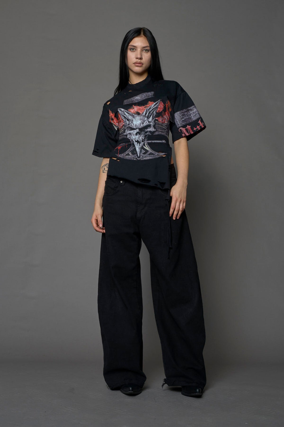 female model wearing a black oversized T-Shirt with a goth-inspired print and a back corset detail