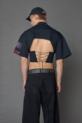 male model wearing a black oversized T-Shirt with a goth-inspired print and a back corset detail