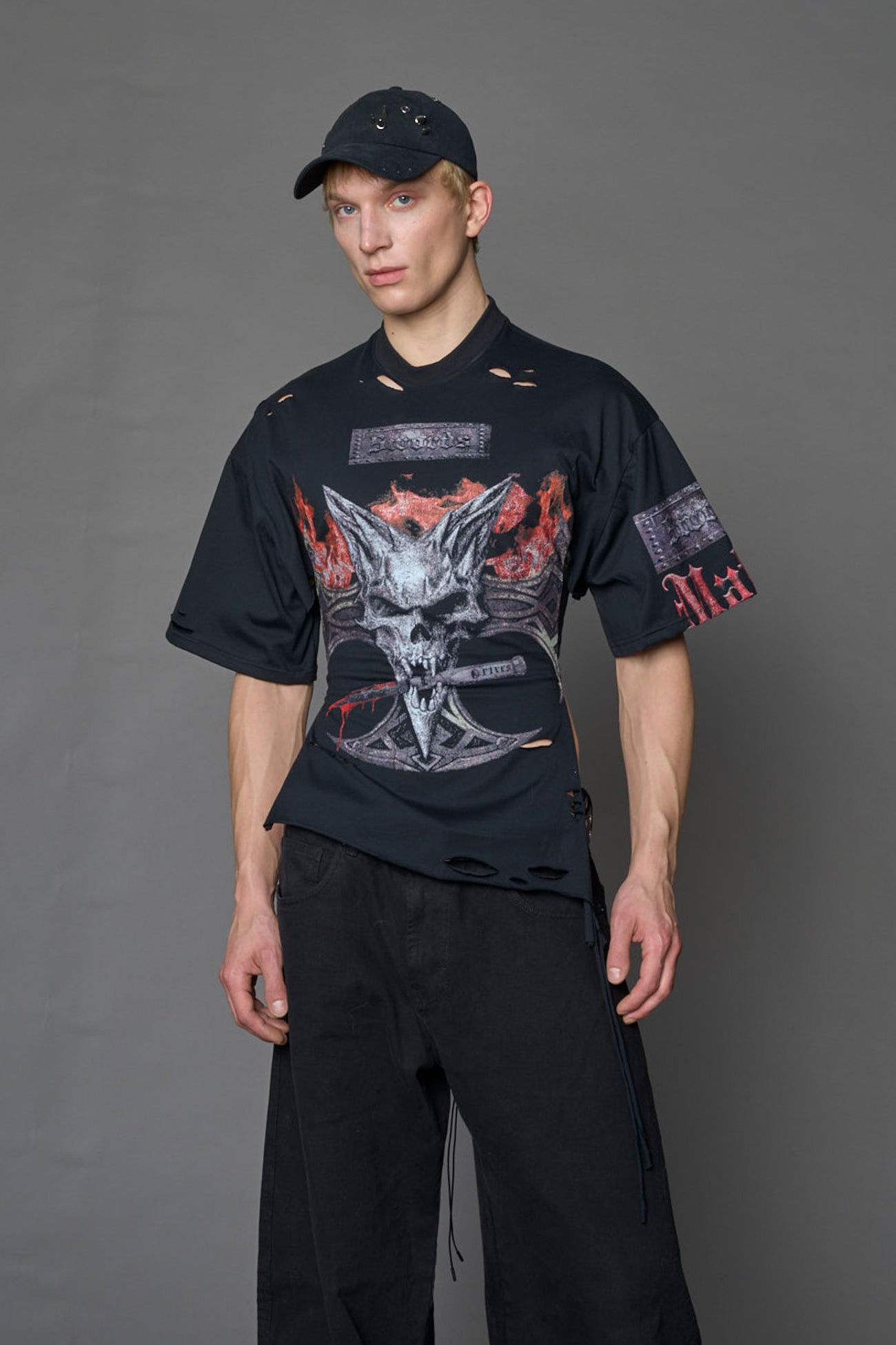 male model wearing a black oversized T-Shirt with a goth-inspired print and a back corset detail