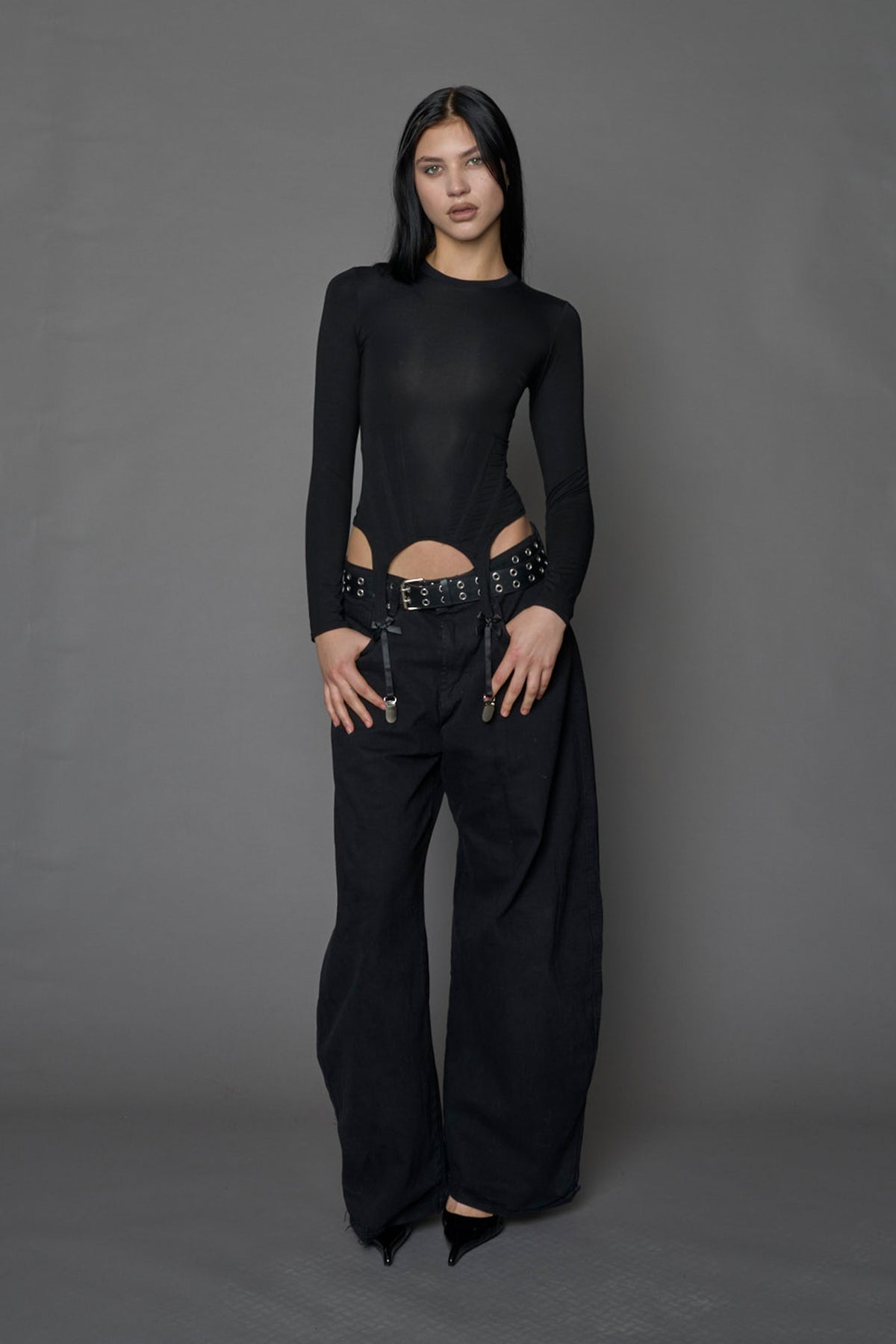 Female model wearing a form fitted lingerie-inspired black longsleeve with garter belt detail