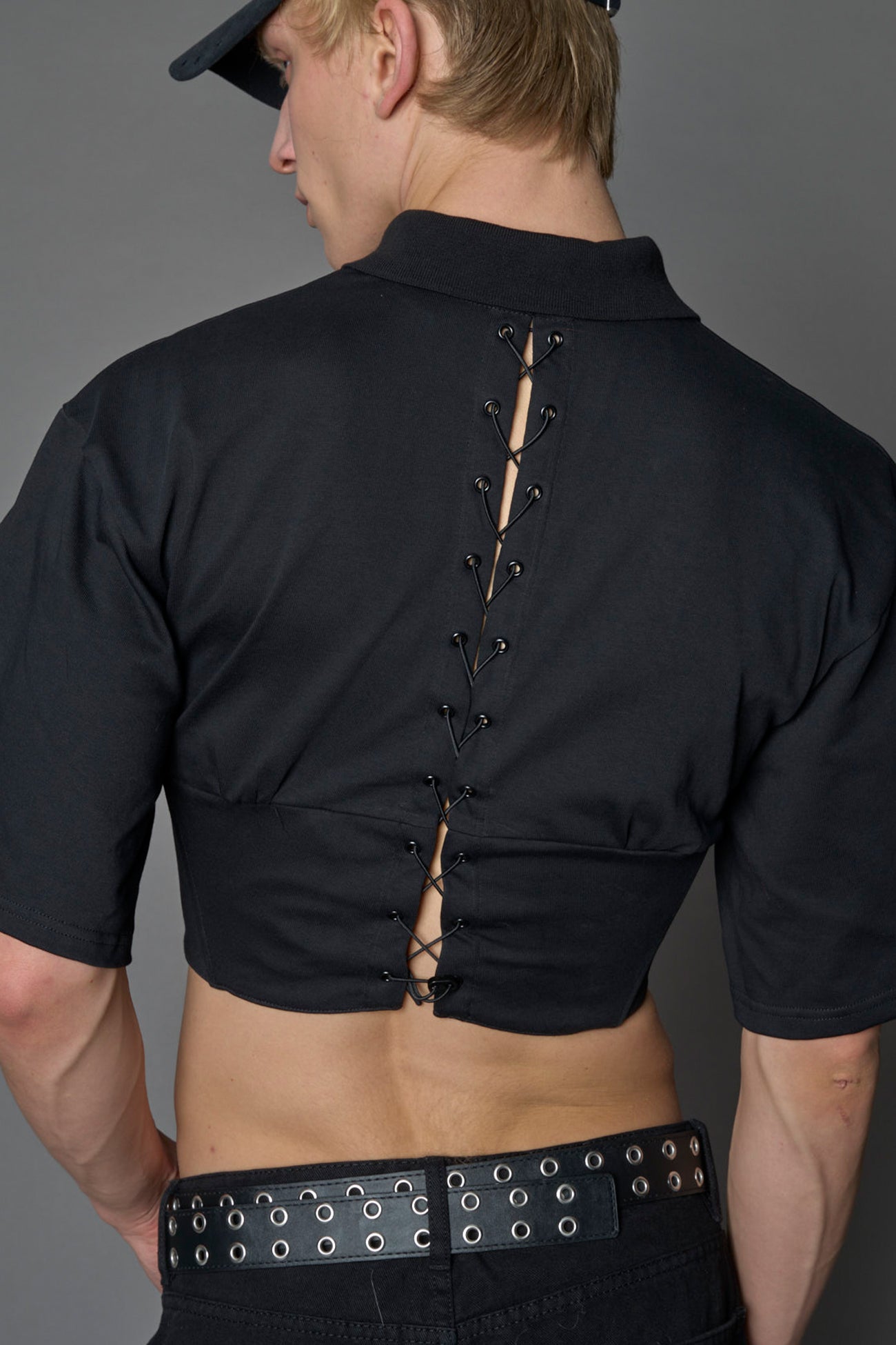 detail of model wearing a Polo shirt inspired black corset with lacing on the back