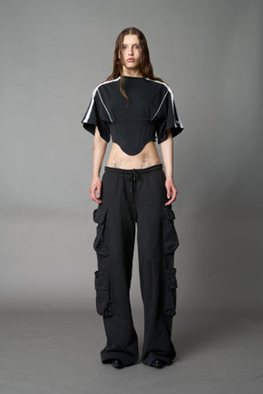 Front view of model in washed-black Namilia Corset-T shirt with sculpted corset-style waist, curved hemline, and oversized sleeves