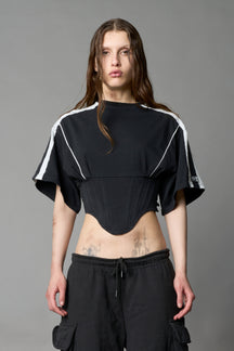 Front view of model in washed-black Namilia Corset-T shirt with sculpted corset-style waist, curved hemline, and oversized sleeves