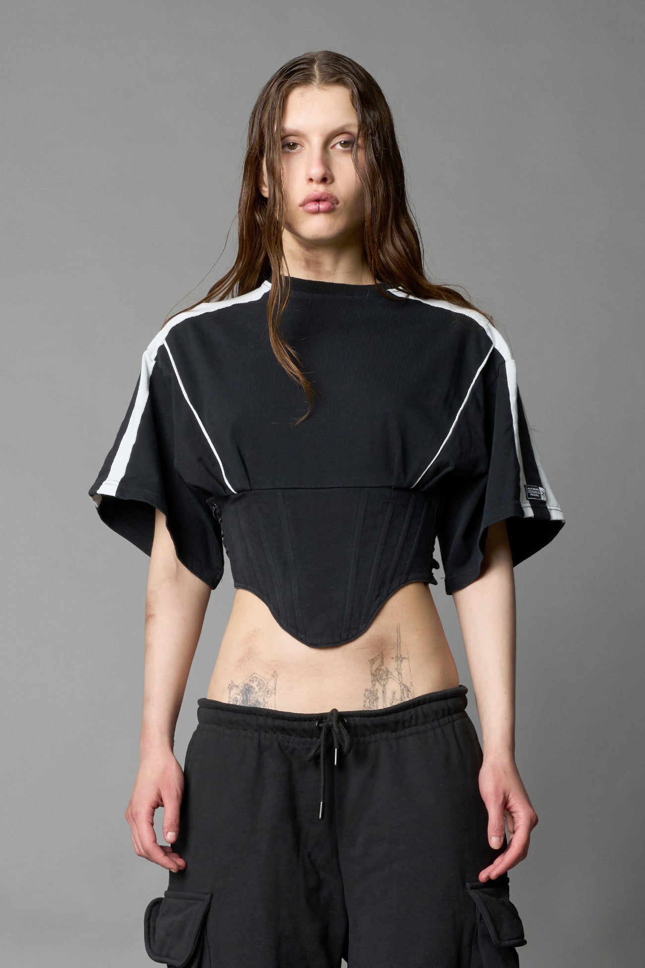 Front view of model in washed-black Namilia Corset-T shirt with sculpted corset-style waist, curved hemline, and oversized sleeves