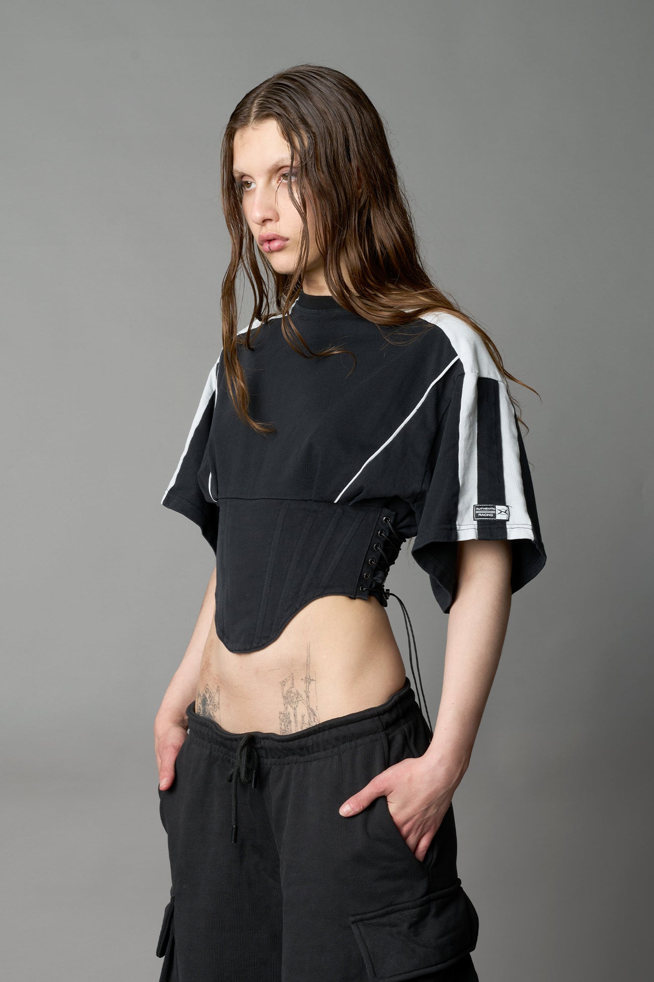 Front view of model in washed-black Namilia Corset-T shirt with sculpted corset-style waist, curved hemline, and oversized sleeves