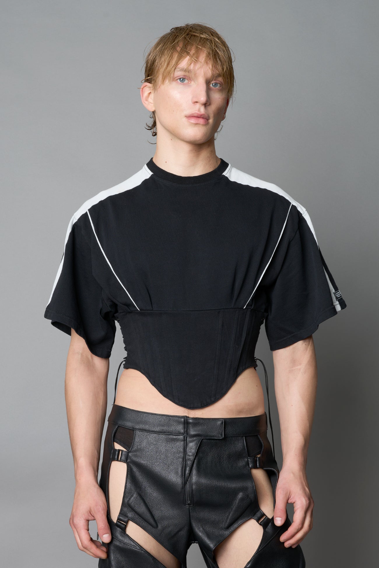 Front view of model in washed-black Namilia Corset-T shirt with sculpted corset-style waist, curved hemline, and oversized sleeves
