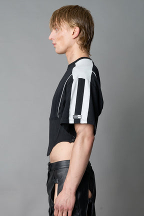 Front view of model in washed-black Namilia Corset-T shirt with sculpted corset-style waist, curved hemline, and oversized sleeves
