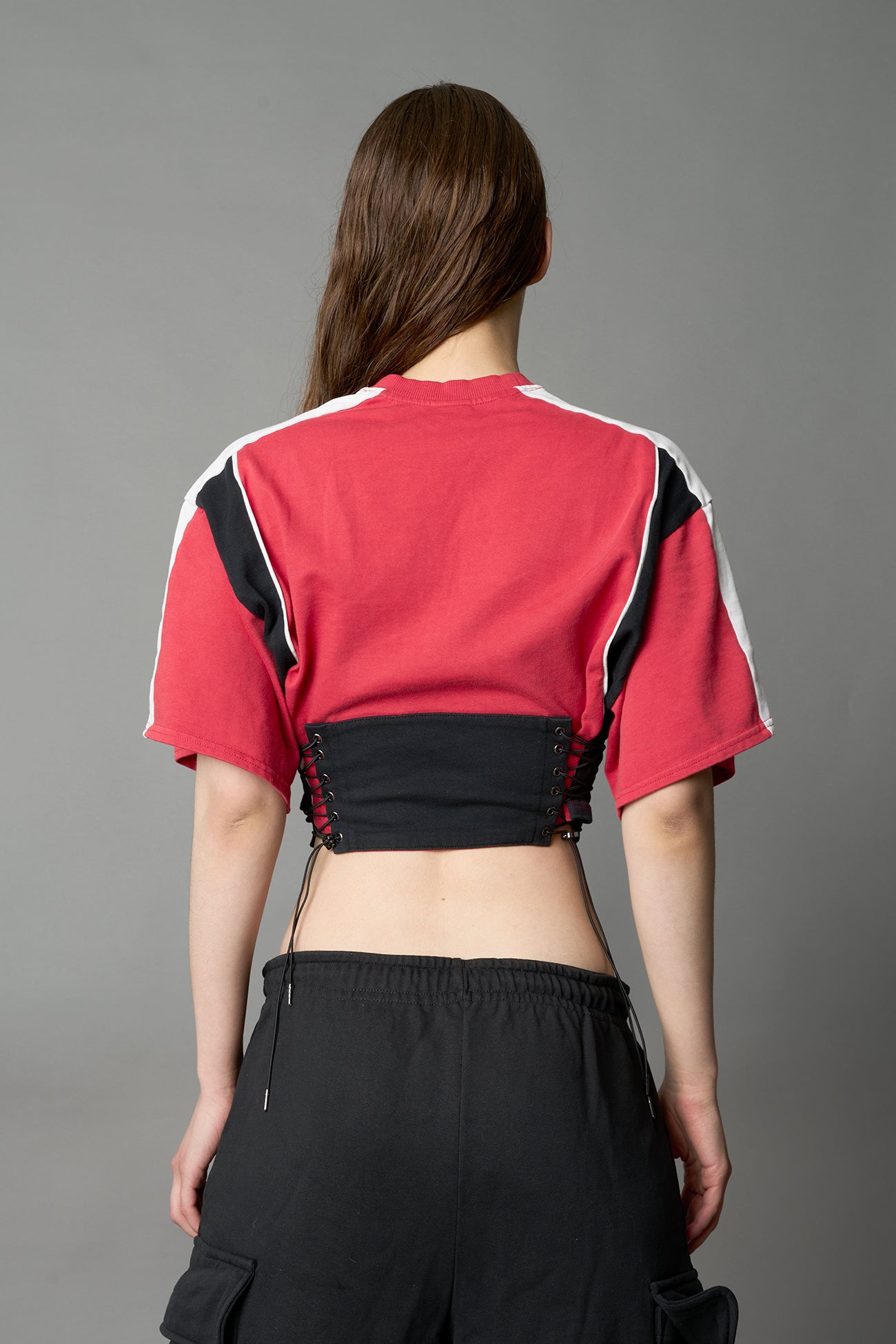 Front view of model in red Namilia Corset-T shirt with sculpted corset-style waist, curved hemline, and oversized sleeves, 