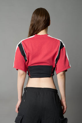 Front view of model in red Namilia Corset-T shirt with sculpted corset-style waist, curved hemline, and oversized sleeves, 