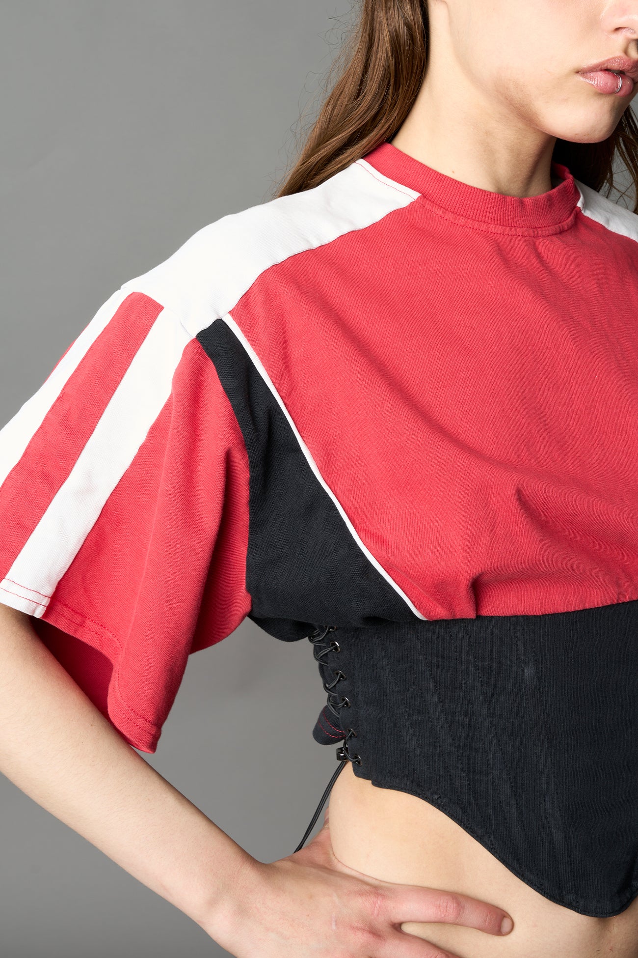 Front view of model in red Namilia Corset-T shirt with sculpted corset-style waist, curved hemline, and oversized sleeves, 