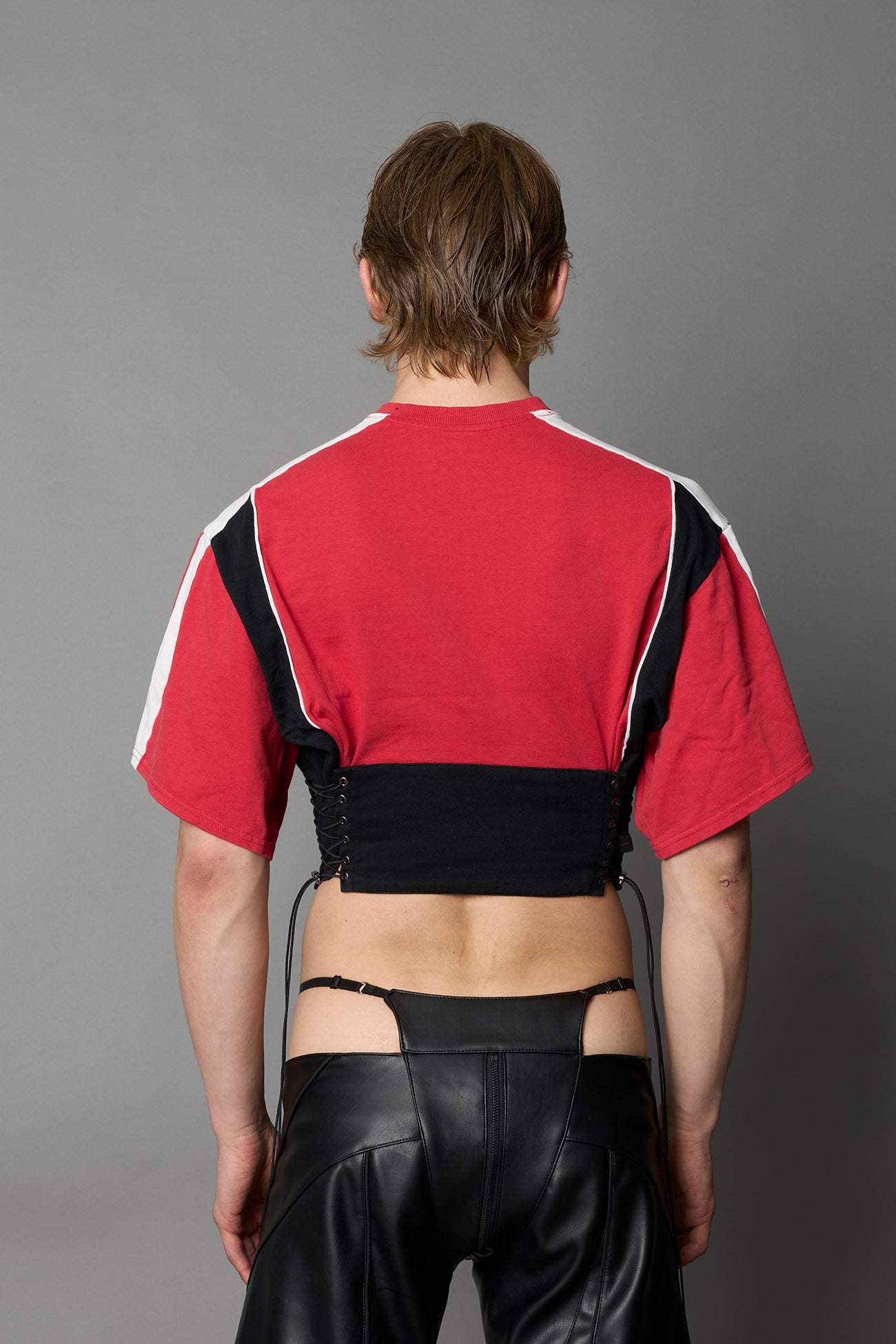 Front view of model in red Namilia Corset-T shirt with sculpted corset-style waist, curved hemline, and oversized sleeves, 