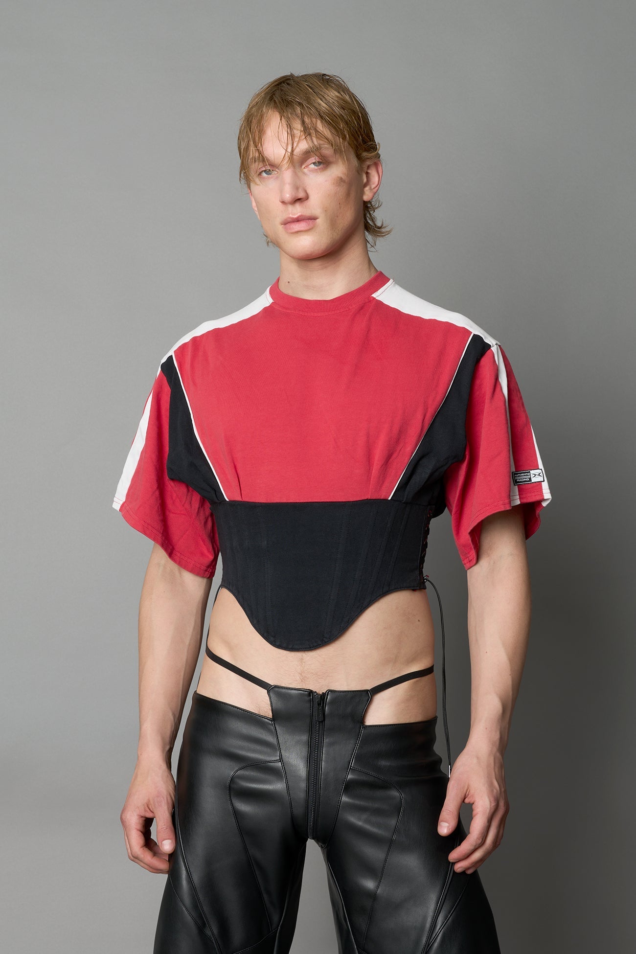 Front view of model in red Namilia Corset-T shirt with sculpted corset-style waist, curved hemline, and oversized sleeves, 