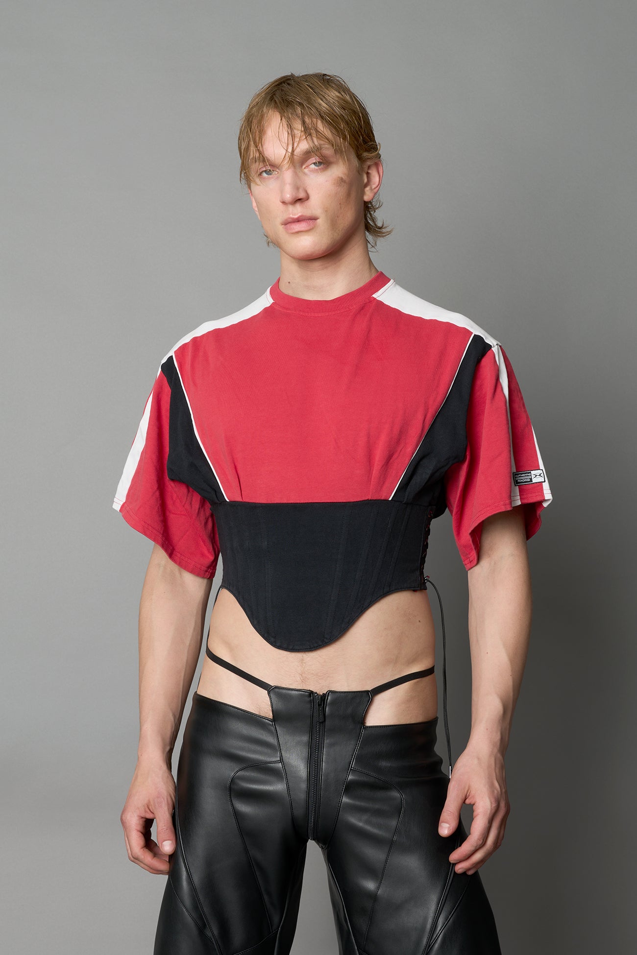Front view of model in red Namilia Corset-T shirt with sculpted corset-style waist, curved hemline, and oversized sleeves, 