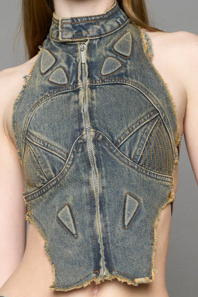 Blue mud denim biker top by NAMILIA with high neck zip front, sculpted corset-style seams, open sides with string lacing, and criss-cross open back, worn by model on neutral background.