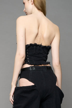 Black dark washed denim cone corset by NAMILIA with spiral-stitched cone cups, strapless fitted silhouette, front zip closure, lace-up sides, and raw frayed edges, worn by model on neutral background.