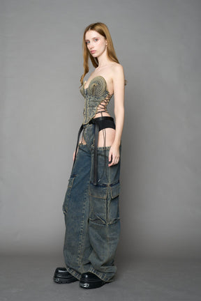 blue mud washed denim cone corset by NAMILIA with spiral-stitched cone cups, strapless fitted silhouette, front zip closure, lace-up sides, and raw frayed edges, worn by model on neutral background.