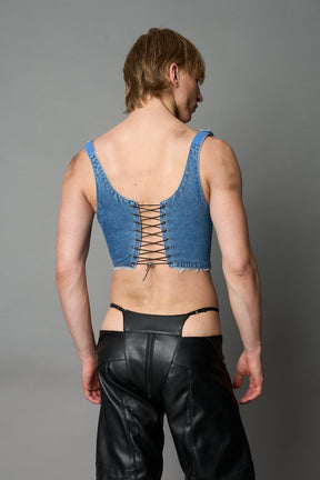 Model wearing blue washed denim corset top with plunging neckline, lace-up front and sides, raw frayed hem, and structured fit