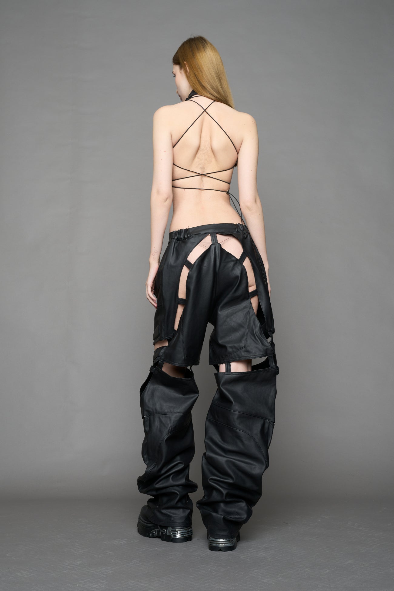 model wearing black coated denim pants with motocross inspired cut outs