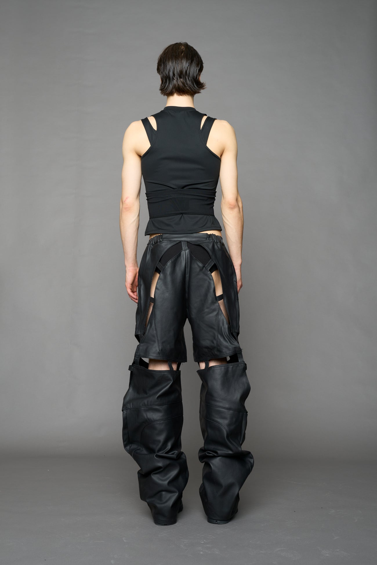 model wearing black coated denim pants with motocross inspired cut outs
