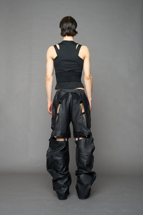 model wearing black coated denim pants with motocross inspired cut outs