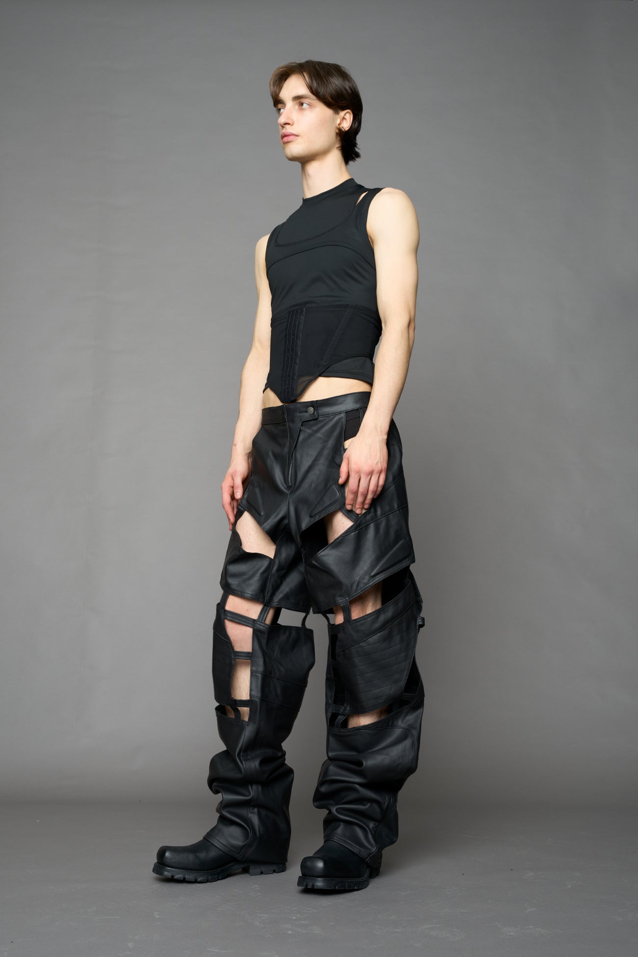 model wearing black coated denim pants with motocross inspired cut outs