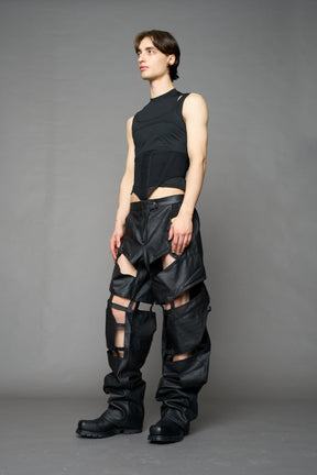 model wearing black coated denim pants with motocross inspired cut outs