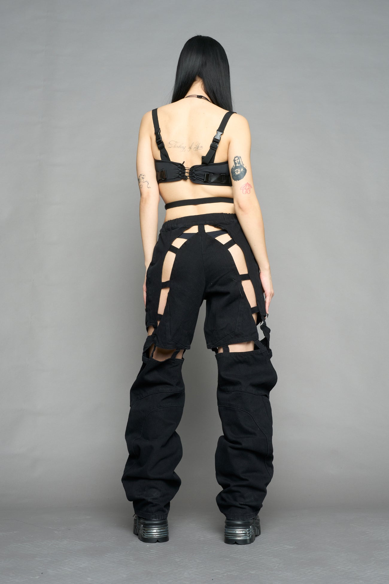 model wearing dark black wash denim pants with motocross inspired cut outs