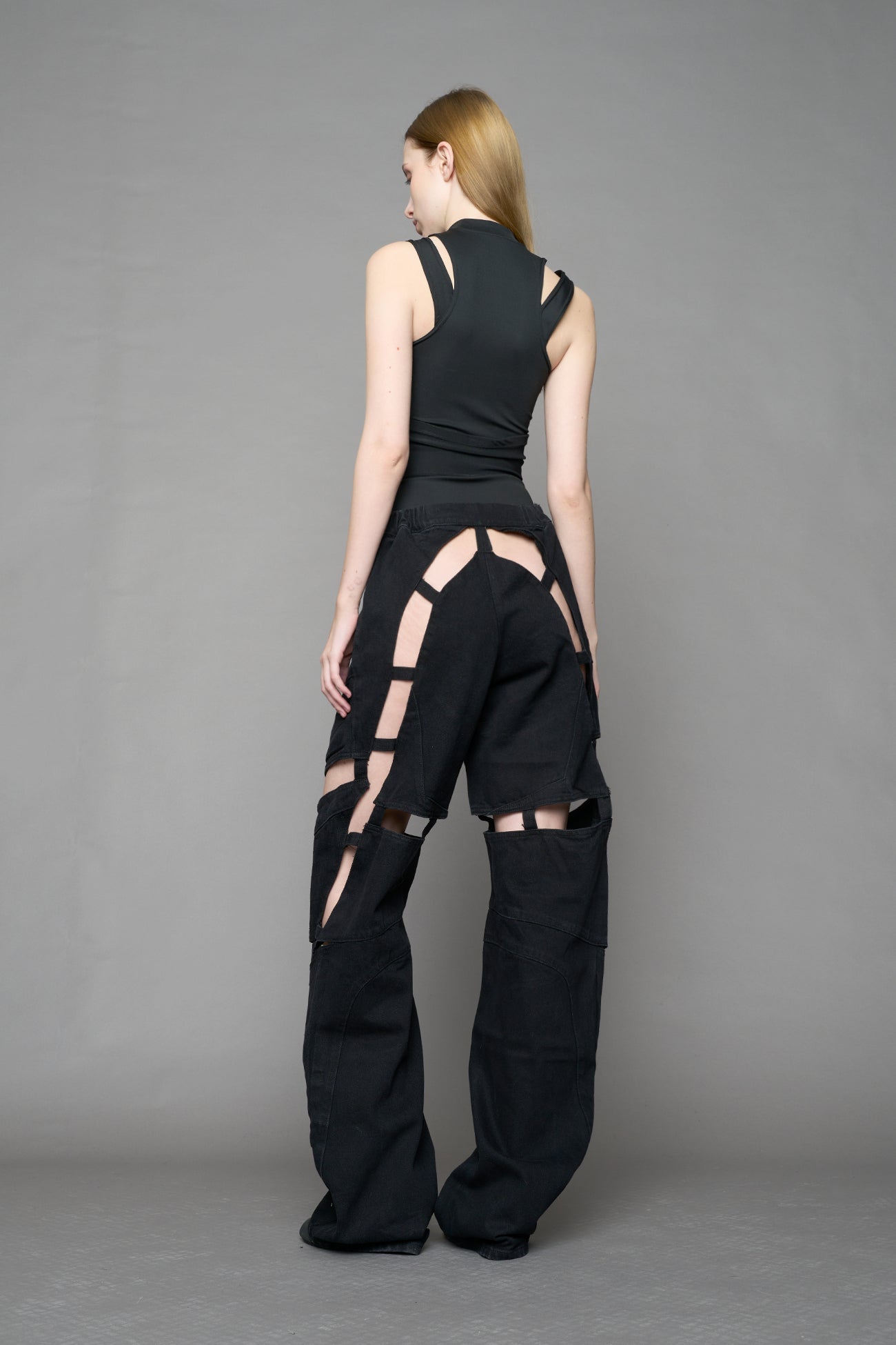 model wearing dark black wash denim pants with motocross inspired cut outs