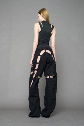 model wearing dark black wash denim pants with motocross inspired cut outs