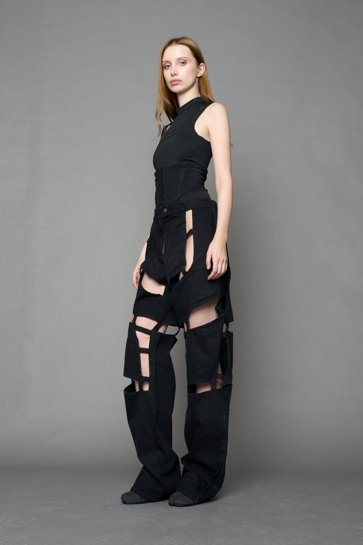 model wearing dark black wash denim pants with motocross inspired cut outs