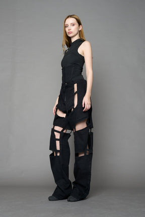 model wearing dark black wash denim pants with motocross inspired cut outs