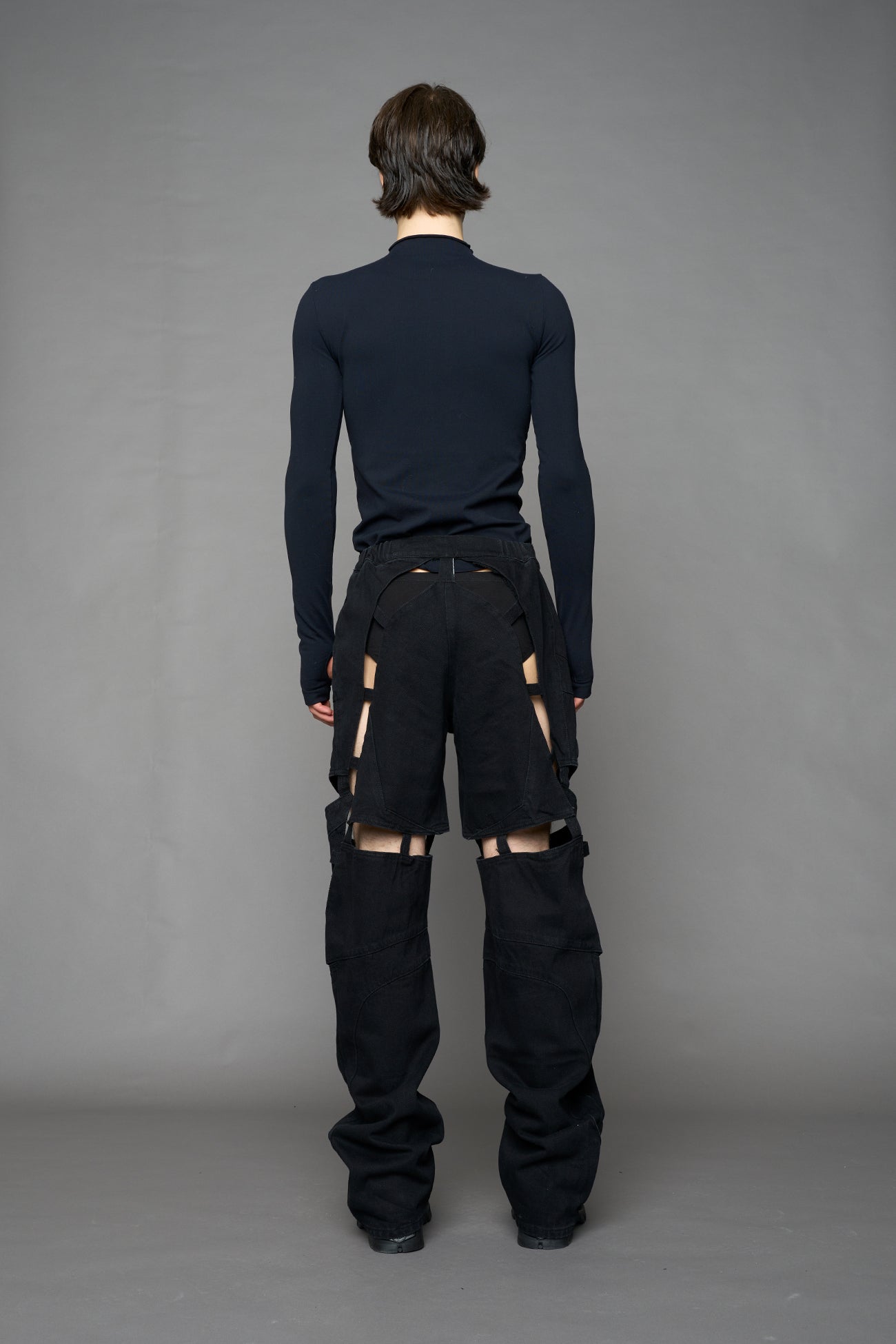 model wearing dark black wash denim pants with motocross inspired cut outs