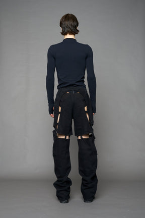 model wearing dark black wash denim pants with motocross inspired cut outs