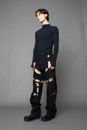 model wearing dark black wash denim pants with motocross inspired cut outs