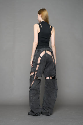 model wearing black washed denim pants with motocross inspired cut outs