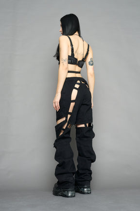model wearing dark black wash denim pants with motocross inspired cut outs