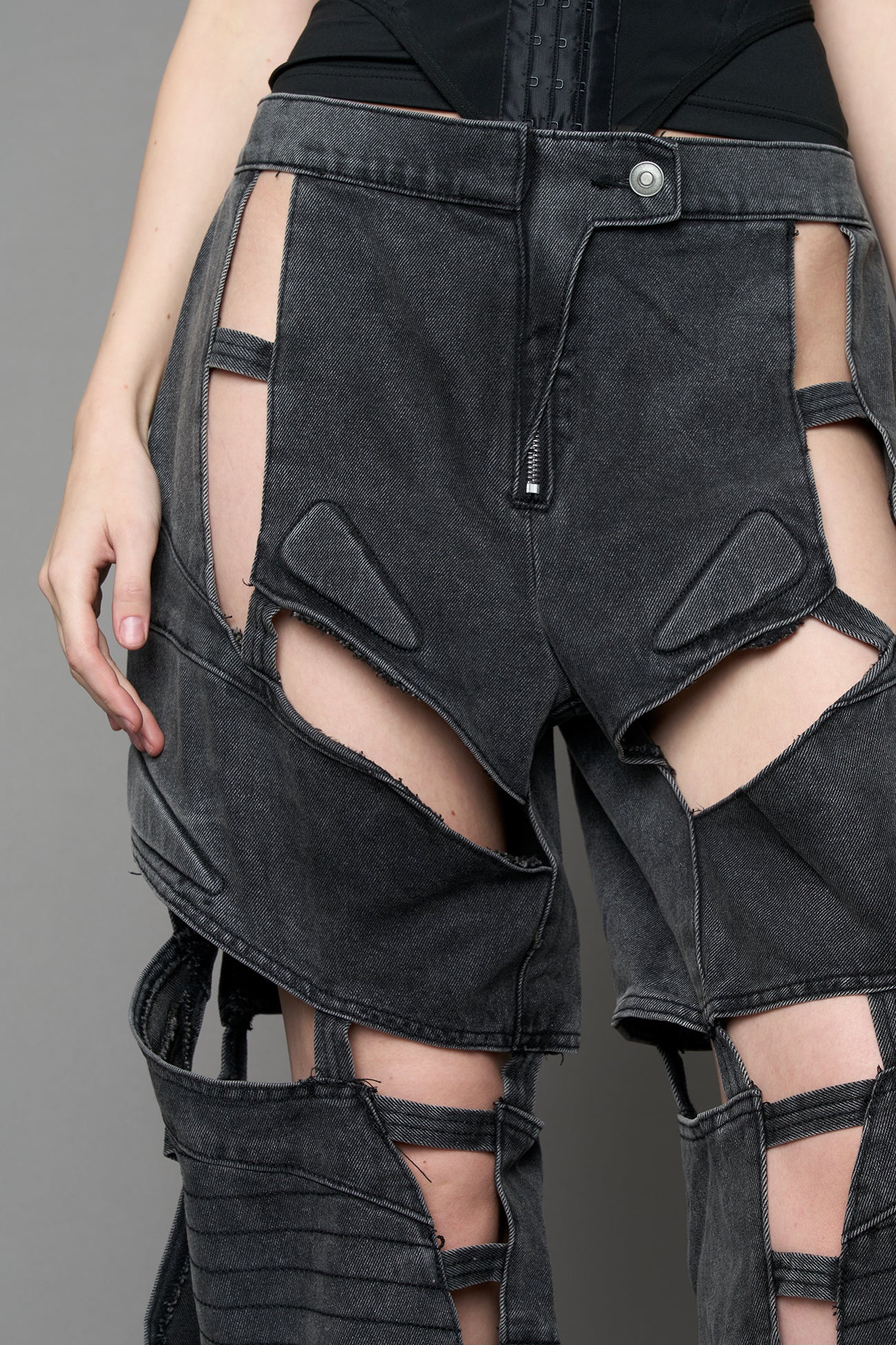 model wearing black washed denim pants with motocross inspired cut outs