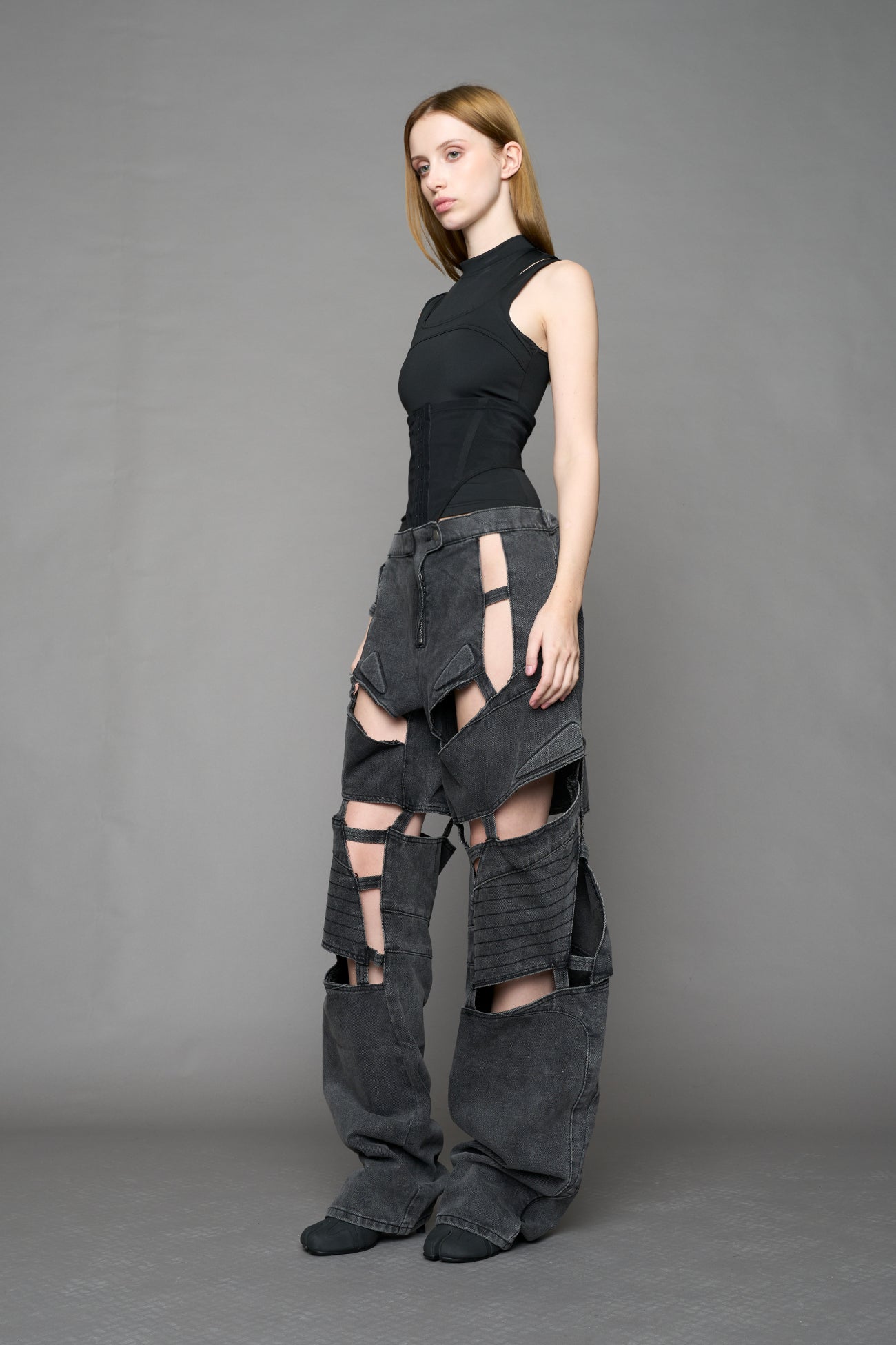 model wearing black washed denim pants with motocross inspired cut outs