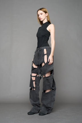 model wearing black washed denim pants with motocross inspired cut outs