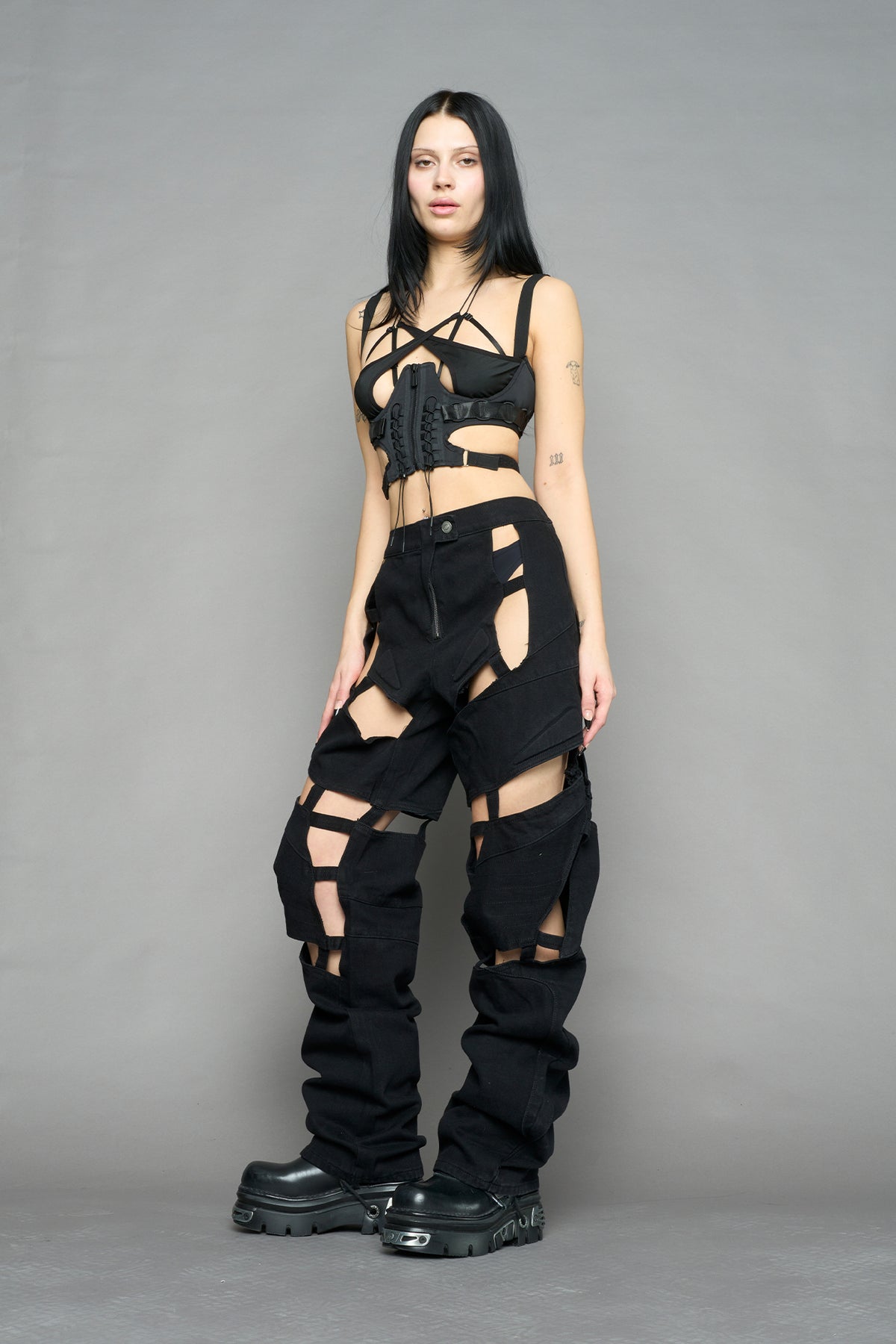 model wearing dark black wash denim pants with motocross inspired cut outs