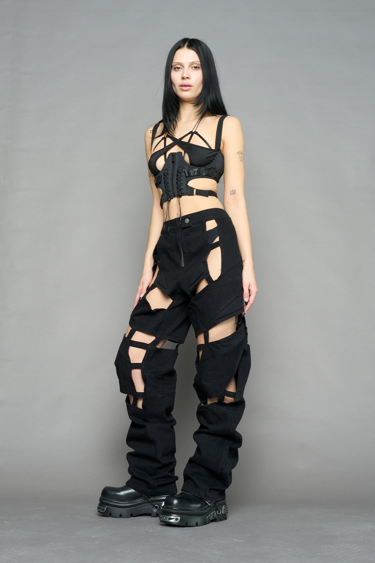 model wearing dark black wash denim pants with motocross inspired cut outs