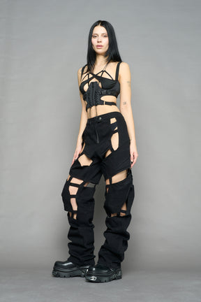 model wearing dark black wash denim pants with motocross inspired cut outs