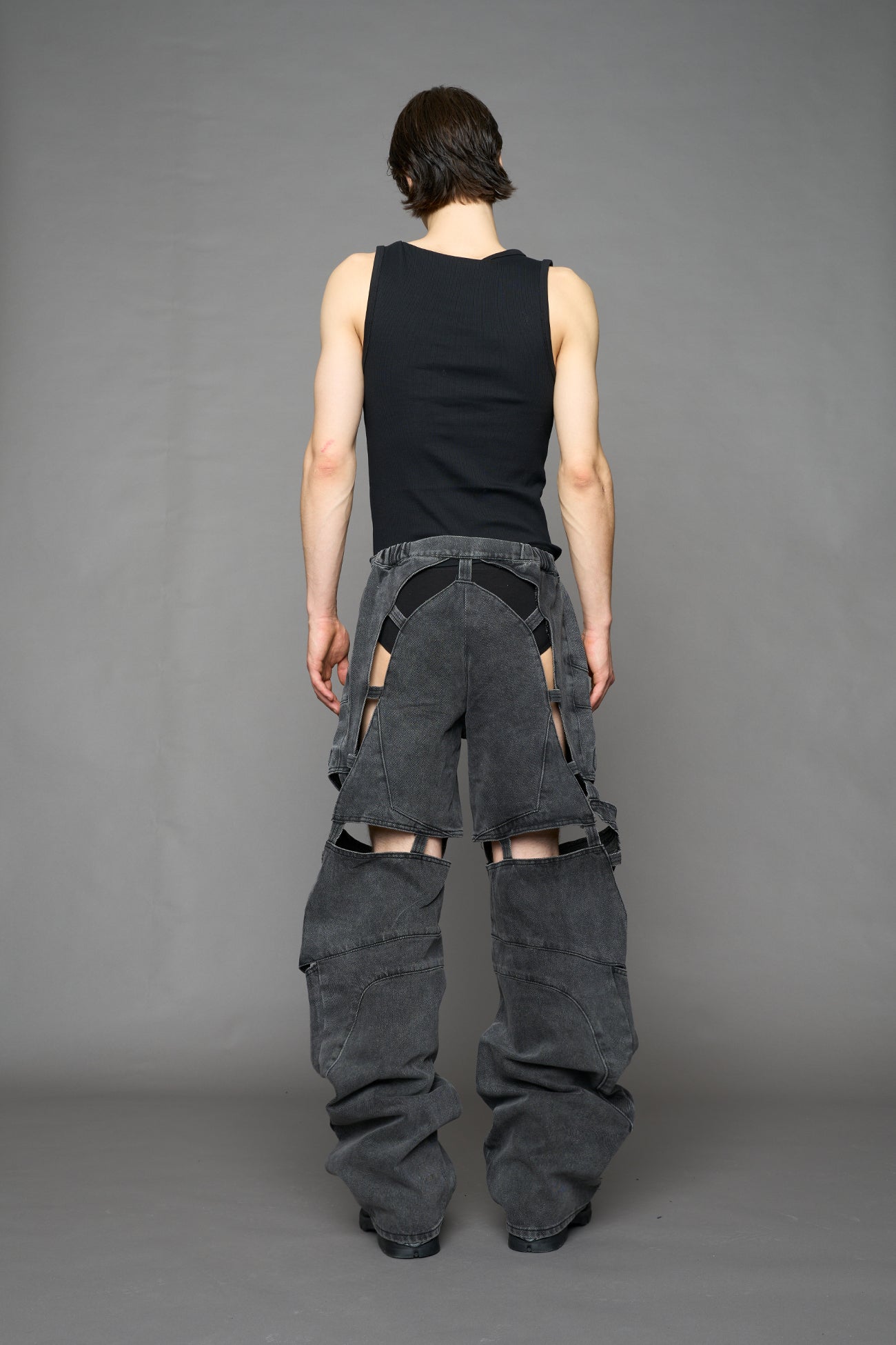 model wearing black washed denim pants with motocross inspired cut outs